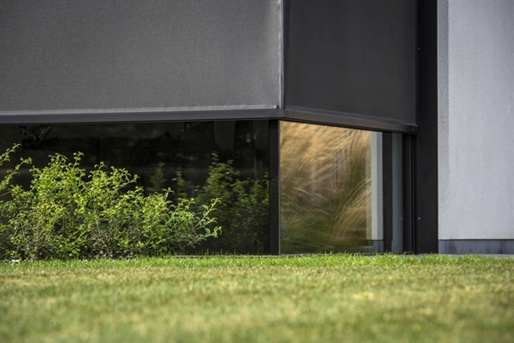 black exterior motorized screen installed on the outside of a glass on glass corner window