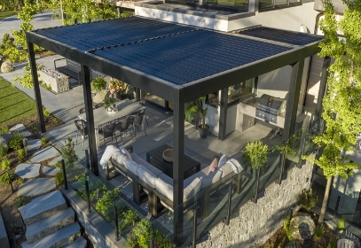 A wall mounted louvered pergola attached to a home overlooking the hills