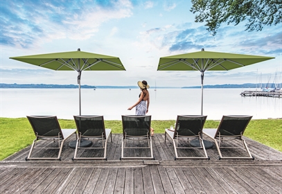 A residential patio with 2 green umbrellas covering the lounge chairs