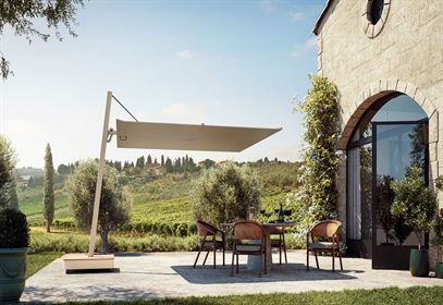 A cream coloured umbrella with a side pole shading the patio of a residence