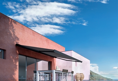 Black coloured retractable awning wall mounted to a red coloured home