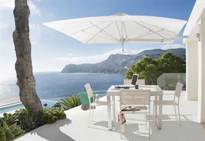 White umbrella wall mounted to the exteior of a white home overlooking the water